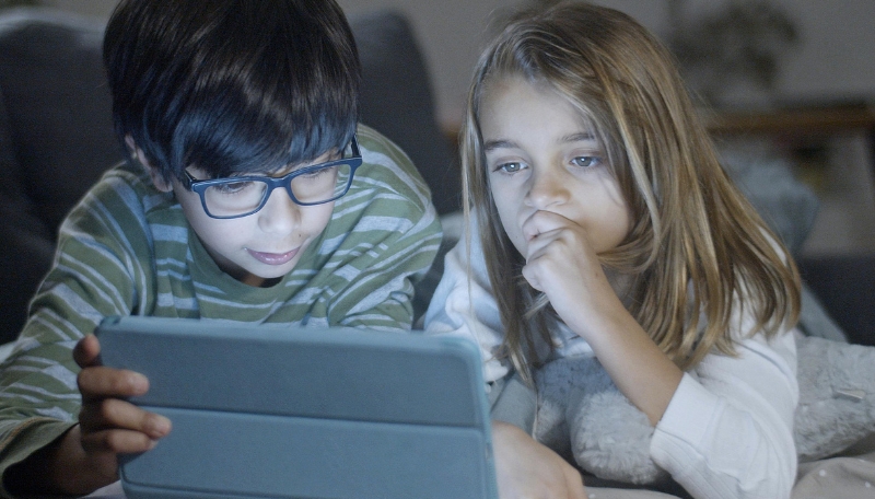 Zwei Kinder liegen vor einem Tablet