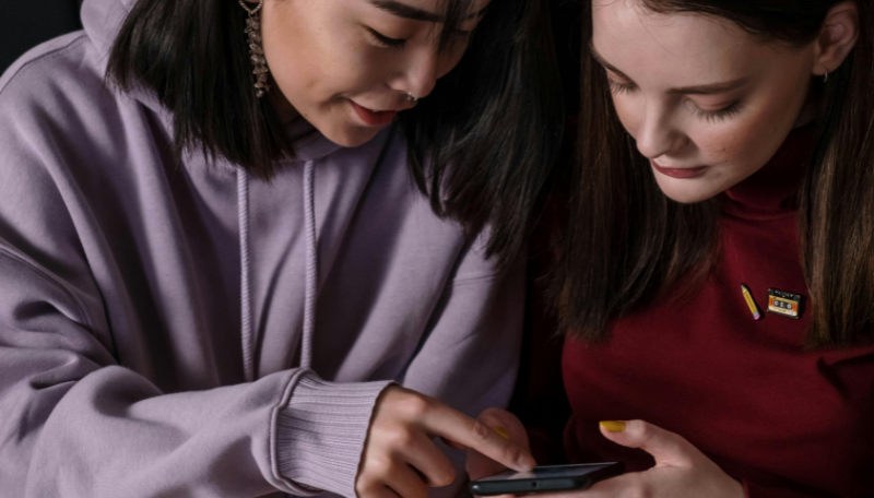 Zwei Jugendliche sehen gemeinsam auf ein Smartphone.
