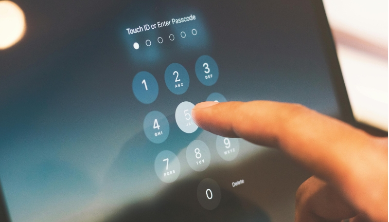 Touchscreen, auf der eine Person gerade ein Zahlenpassort eingibt. Man sieht wie eine Hand gerade auf die Zahl 5 klickt